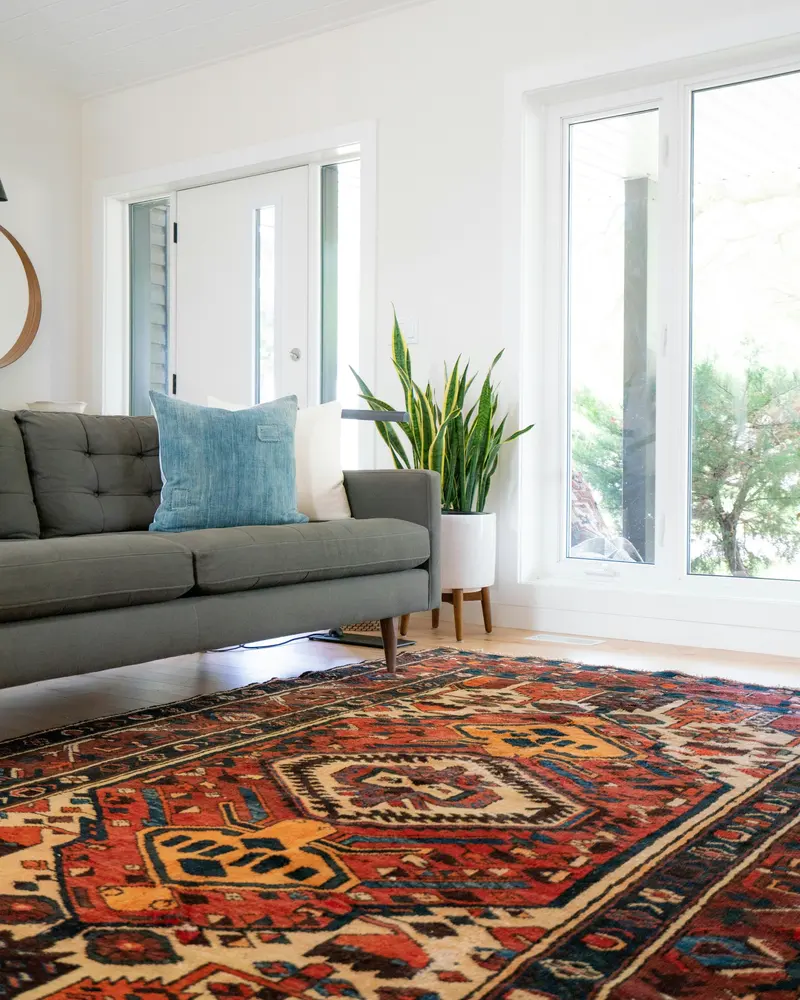 Sala com sofá cinza e tapete persa vermelho